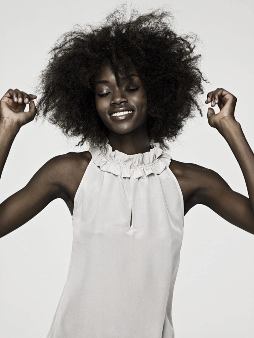 Joyful woman with natural afro hairstyle in a sleeveless top.