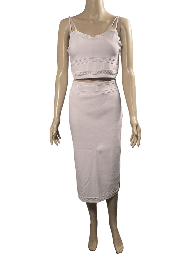 Woman wearing a white sleeveless crop top and matching midi skirt.