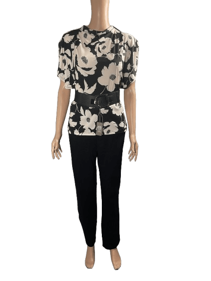 Woman in a black and white floral blouse and black pants.