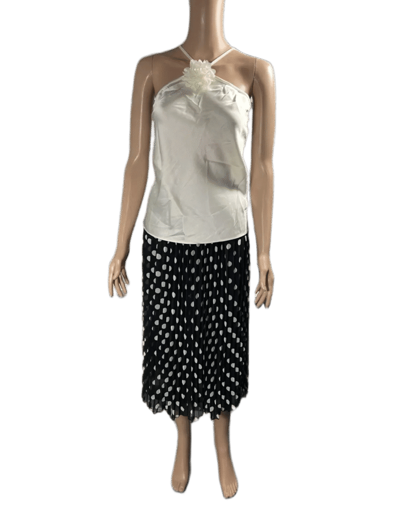 Woman wearing a white satin top and black polka dot skirt.