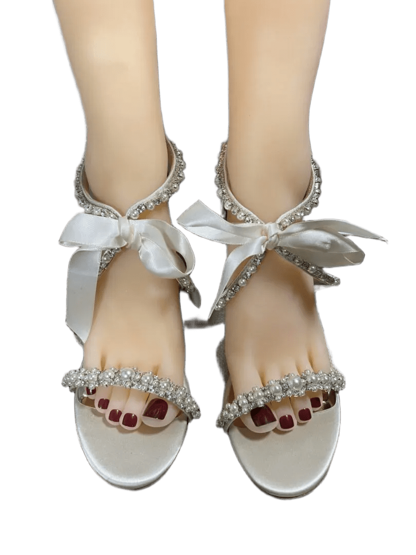 Elegant white sandals with ankle ribbons and red toenail polish.