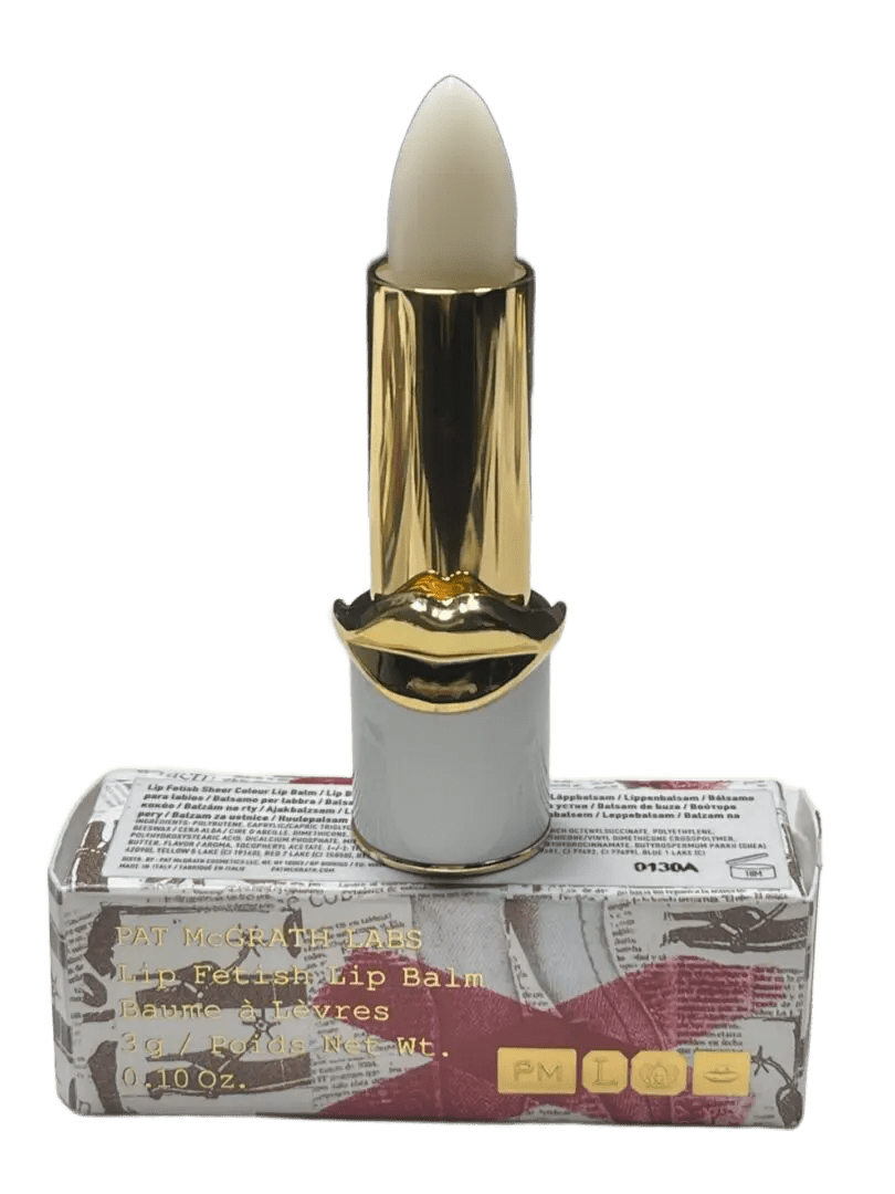 A candle shaped like a golden lipstick atop a clear block.