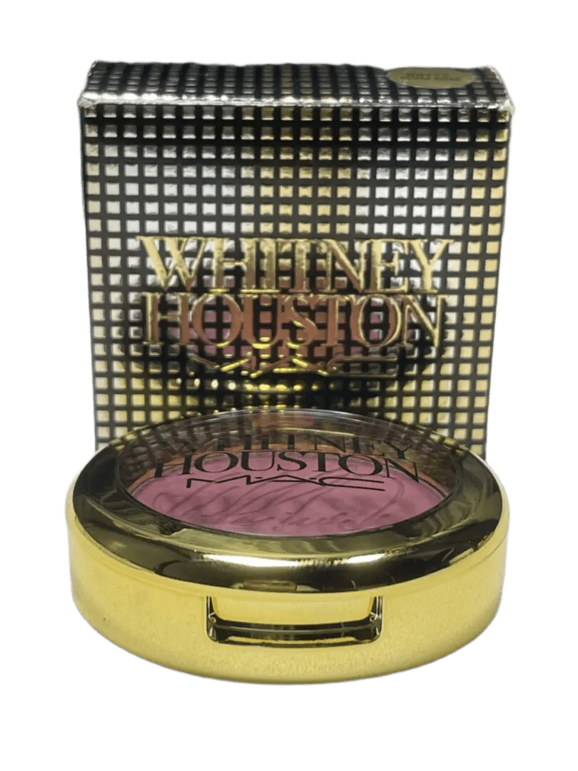 Compact makeup blush with a textured purple powder inside a gold and patterned case.