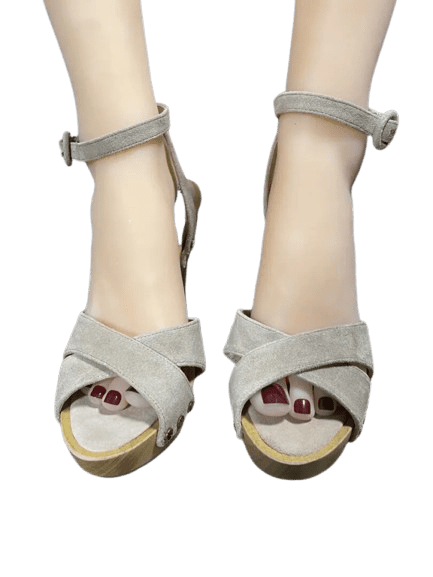 Feet wearing beige sandals with red toenail polish.