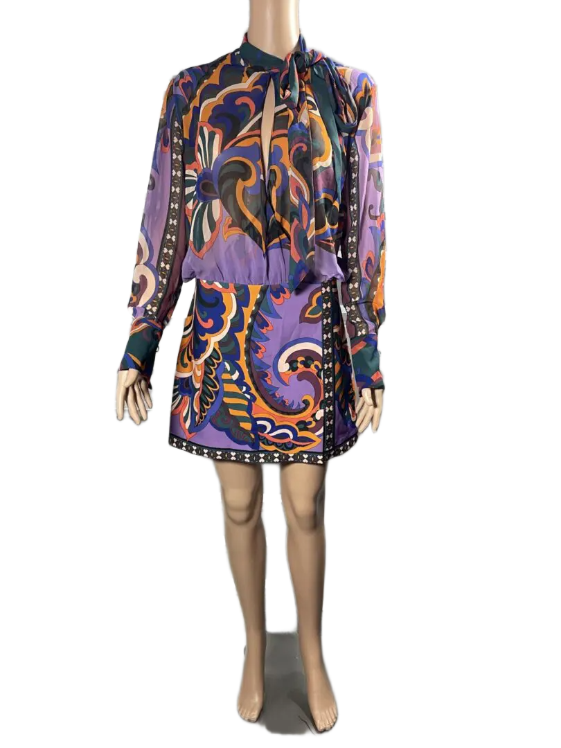 Woman wearing a colorful paisley-patterned dress with long sleeves.