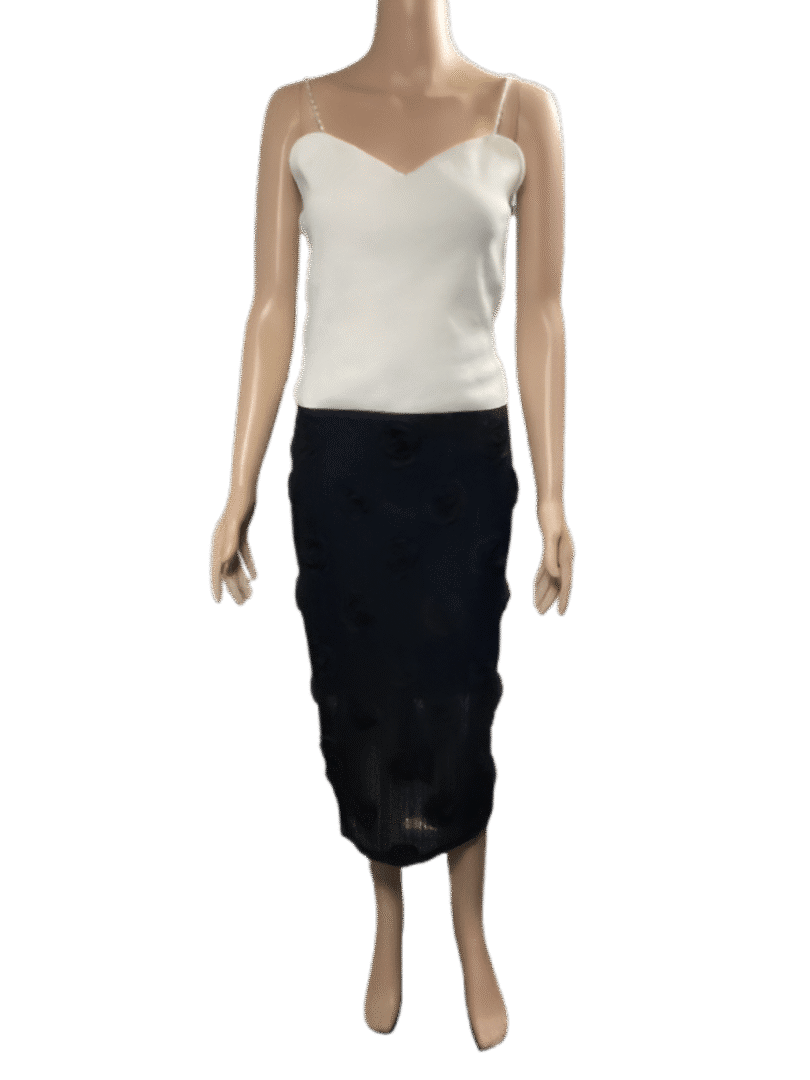 Woman wearing a white camisole and a black lace skirt.