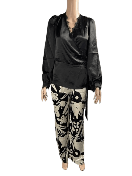 Person wearing a black satin blouse and floral patterned pants.